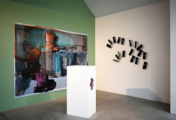 A large photograph, 18 small playing cards on the wall, a sculpture on the ground